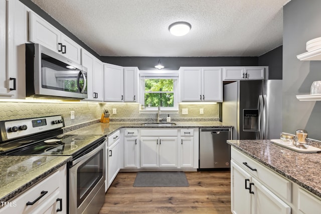 kitchen with stainless steel appliances, a textured ceiling, white cabinetry, and a sink