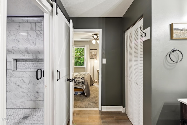 ensuite bathroom with ensuite bath, a ceiling fan, baseboards, a shower stall, and wood finished floors