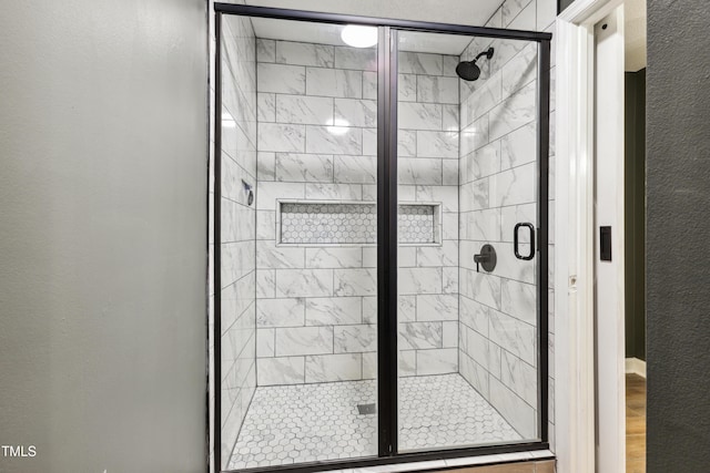 bathroom with wood finished floors and a shower stall