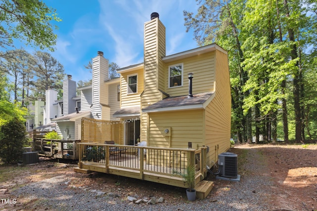 rear view of property with cooling unit, a chimney, and a wooden deck