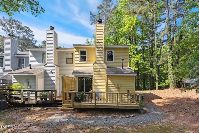 back of house featuring a wooden deck and a chimney
