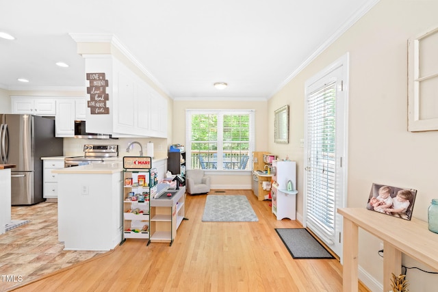 interior space with ornamental molding, light wood-type flooring, light countertops, white cabinetry, and appliances with stainless steel finishes