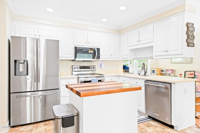 kitchen with wooden counters, crown molding, a sink, white cabinets, and stainless steel appliances