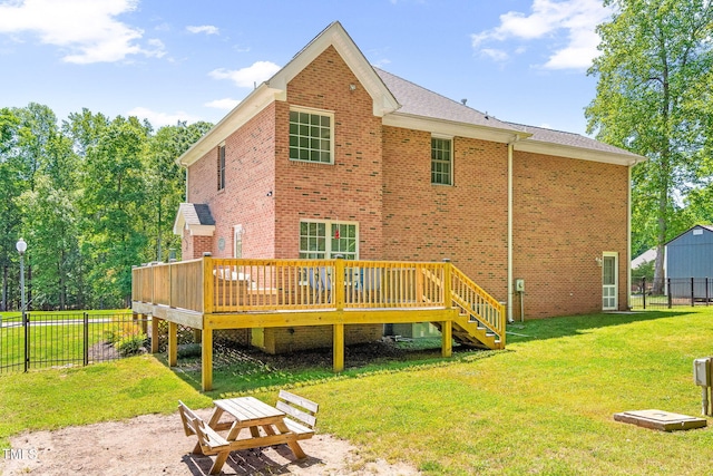 back of property featuring fence, a wooden deck, a lawn, and brick siding
