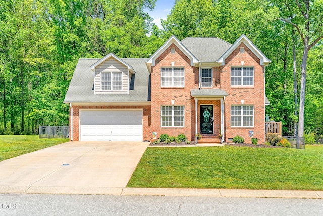 colonial home with fence, an attached garage, brick siding, a front yard, and concrete driveway