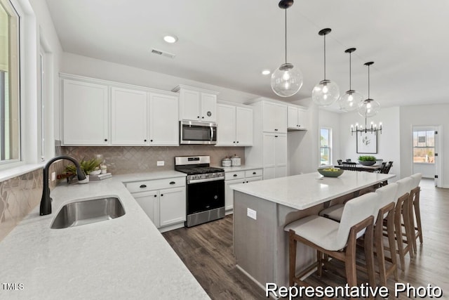 kitchen with visible vents, a sink, white cabinets, stainless steel appliances, and dark wood-type flooring