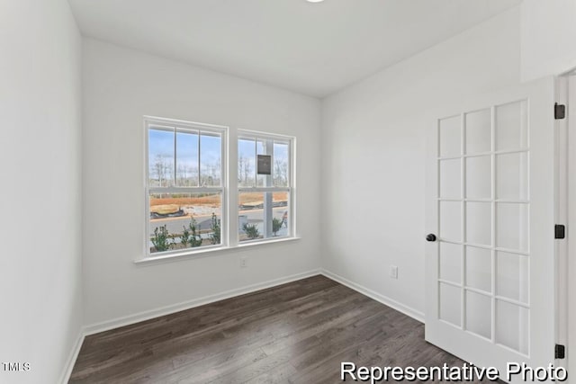 empty room featuring baseboards and dark wood finished floors