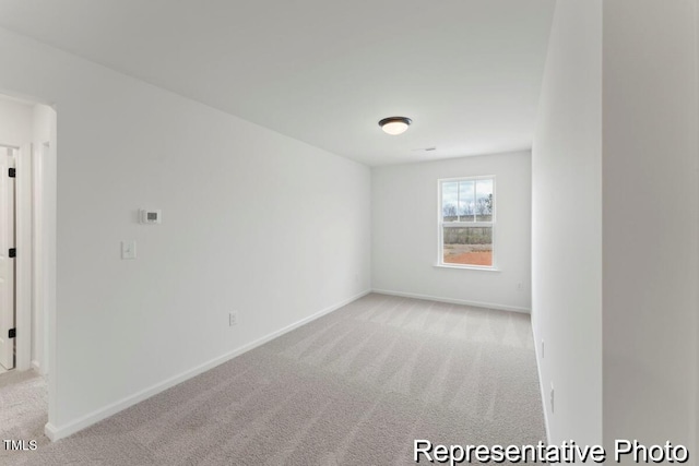 empty room featuring light colored carpet and baseboards