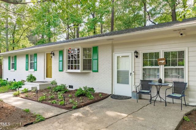 view of front of property featuring crawl space, a patio, and brick siding