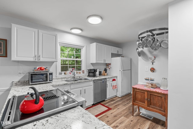 kitchen with appliances with stainless steel finishes, a sink, and white cabinets