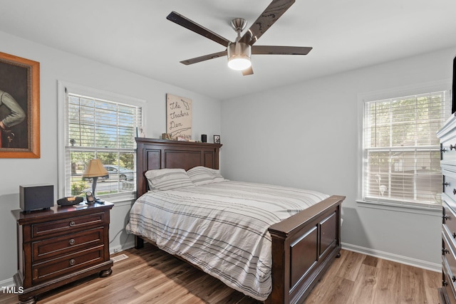 bedroom with light wood finished floors, baseboards, and a ceiling fan