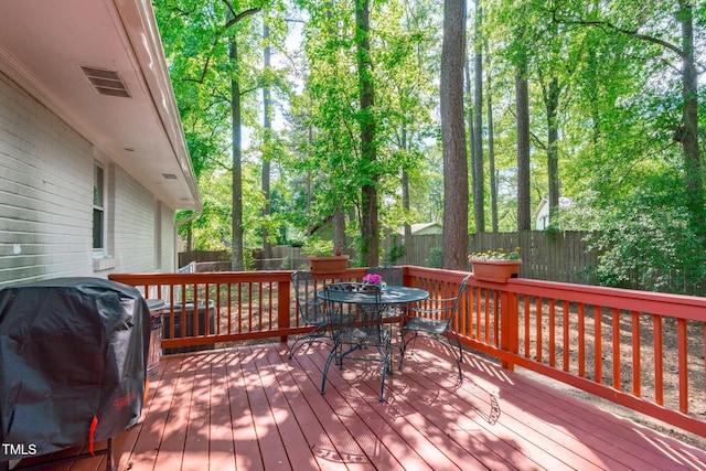 wooden deck with a grill, a fenced backyard, and outdoor dining space