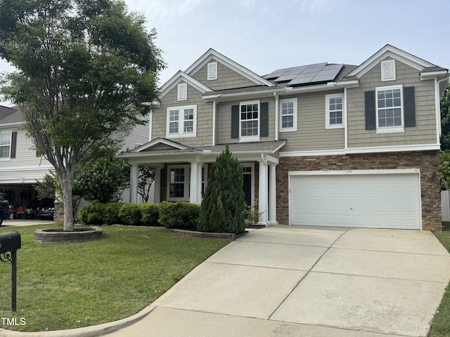 view of front facade with a front lawn, solar panels, an attached garage, concrete driveway, and stone siding