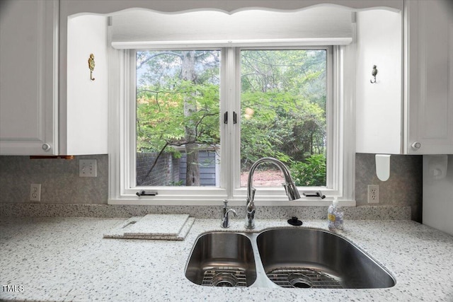 3025 Wycliff Rd, Raleigh, NC 27607 - kitchen with a sink, light stone counters, backsplash, and white cabinets