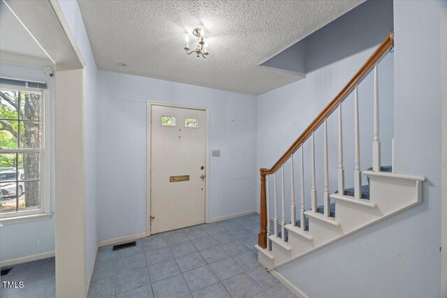 3025 Wycliff Rd, Raleigh, NC 27607 - tiled foyer entrance featuring a textured ceiling, stairs, and baseboards