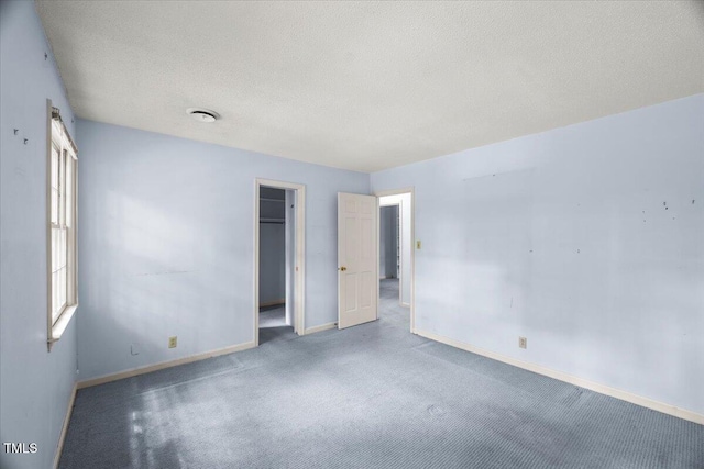 3025 Wycliff Rd, Raleigh, NC 27607 - unfurnished bedroom featuring baseboards, carpet, a textured ceiling, a closet, and a walk in closet