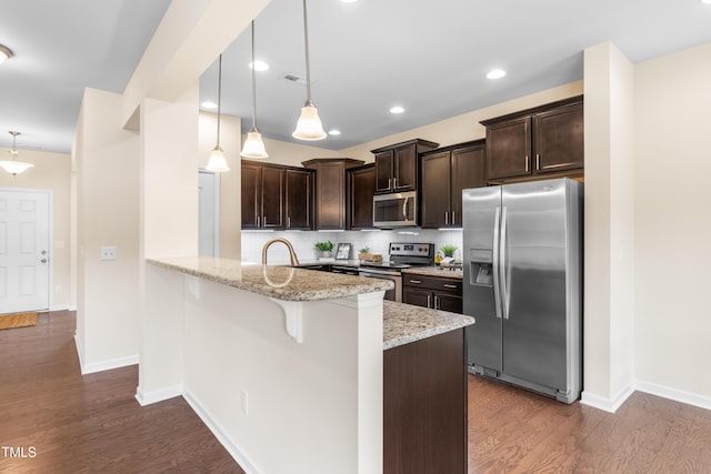 1104 Arden Trace Ct, Fuquay Varina, NC 27526 - kitchen featuring appliances with stainless steel finishes, dark brown cabinetry, light stone counters, dark wood-style floors, and tasteful backsplash