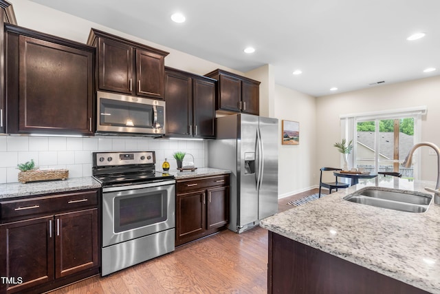 1104 Arden Trace Ct, Fuquay Varina, NC 27526 - kitchen with stainless steel appliances, a sink, wood finished floors, light stone counters, and tasteful backsplash