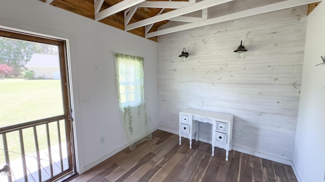 unfurnished office featuring baseboards, wood walls, and wood finished floors