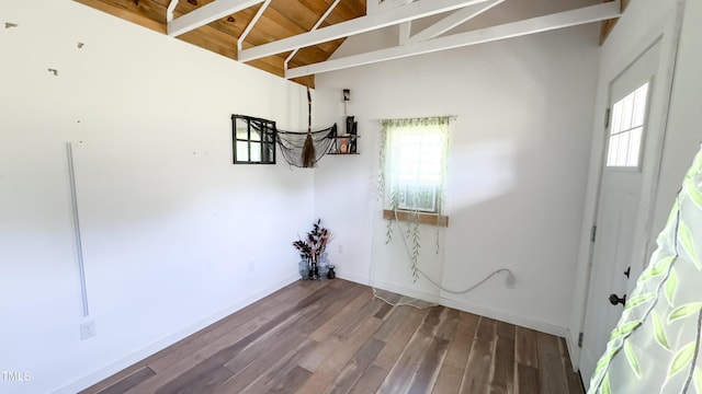 interior space featuring baseboards, vaulted ceiling with beams, wood finished floors, and a wealth of natural light