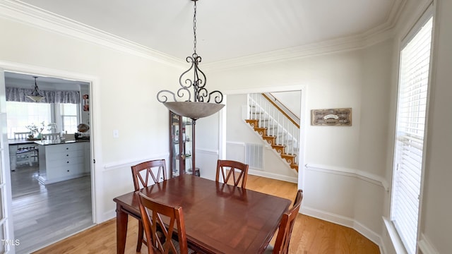 dining area featuring visible vents, ornamental molding, and light wood finished floors
