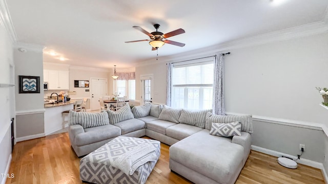 living area with crown molding, light wood finished floors, ceiling fan, and baseboards