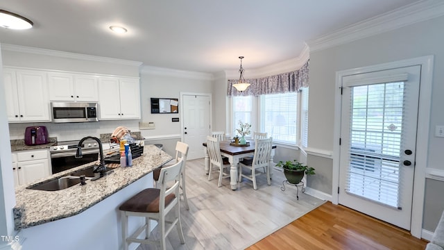 kitchen with crown molding, a sink, appliances with stainless steel finishes, and light wood-type flooring