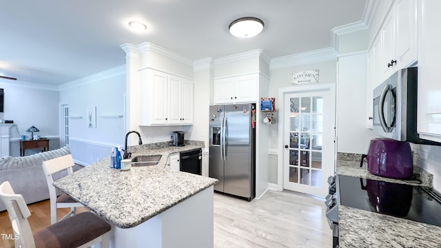 kitchen with a kitchen bar, a sink, a peninsula, open floor plan, and stainless steel appliances