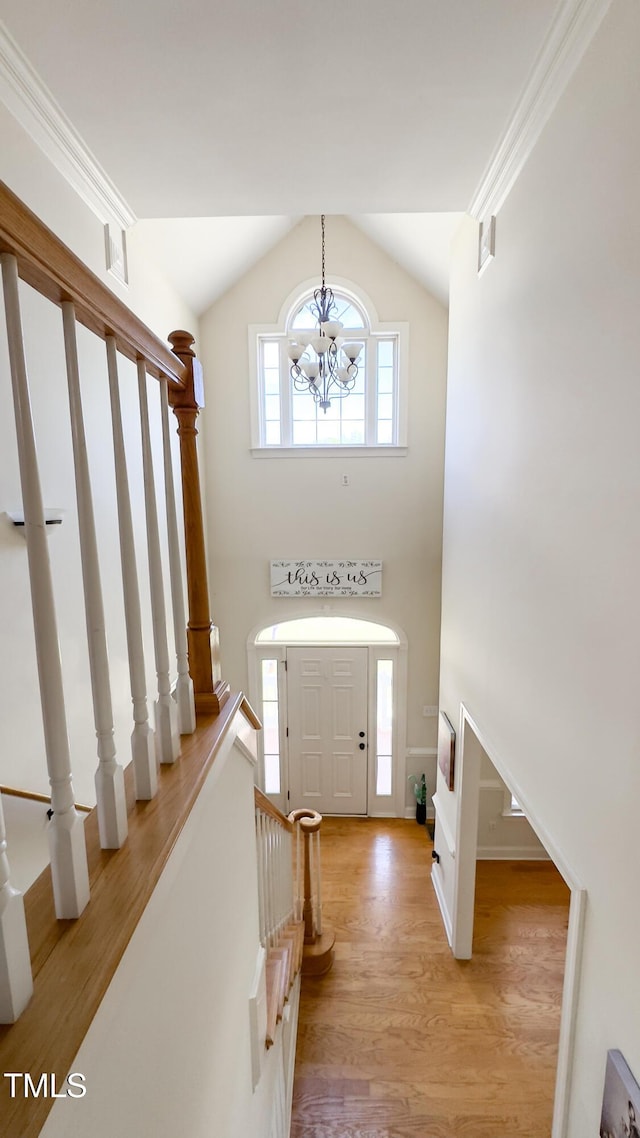 foyer featuring an inviting chandelier, light wood-style floors, high vaulted ceiling, and stairway