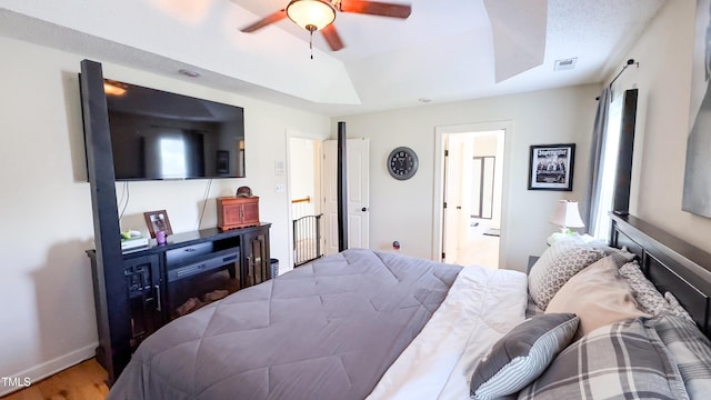 bedroom featuring a ceiling fan, visible vents, a skylight, wood finished floors, and baseboards