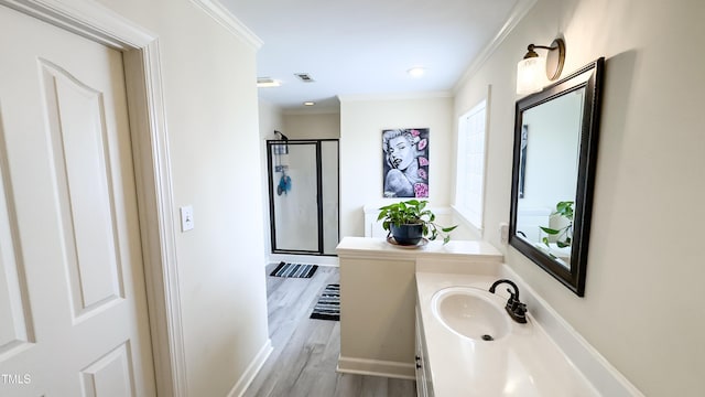 full bath with vanity, wood finished floors, visible vents, ornamental molding, and a stall shower