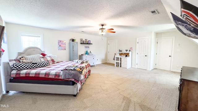 bedroom featuring light carpet, a textured ceiling, and visible vents