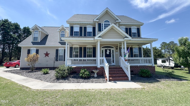 view of front facade with a porch, a shingled roof, and a front yard