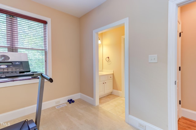 exercise room featuring light colored carpet and baseboards