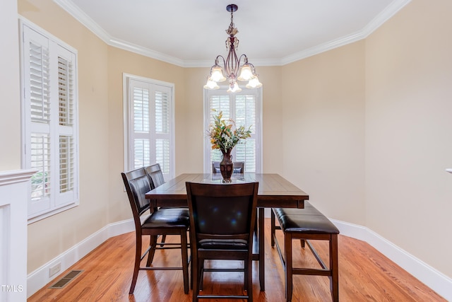 dining space featuring a chandelier, light wood-style flooring, ornamental molding, and baseboards