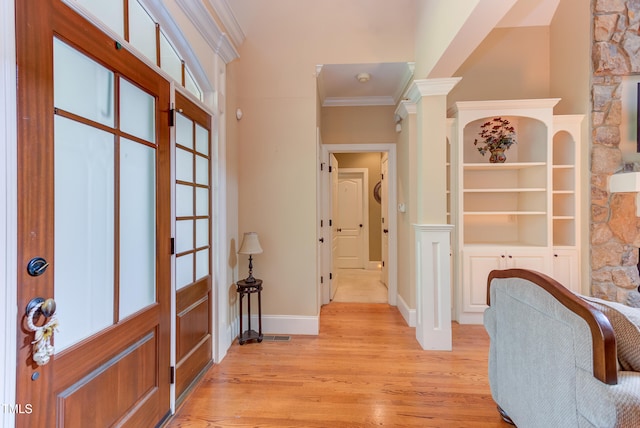 foyer entrance with ornamental molding, light wood-style floors, baseboards, and decorative columns