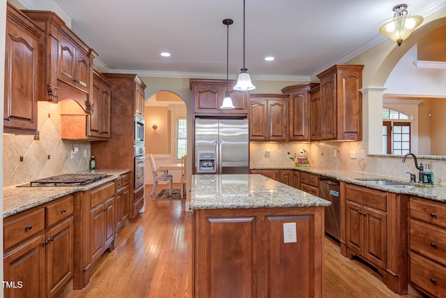 kitchen with appliances with stainless steel finishes, arched walkways, a sink, a center island, and light stone counters