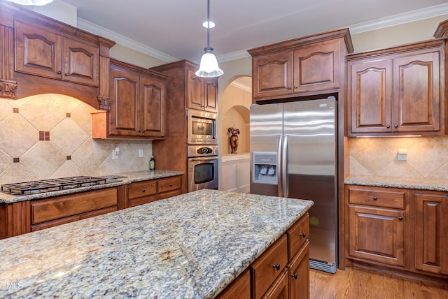 kitchen with stainless steel appliances, light stone countertops, pendant lighting, and crown molding