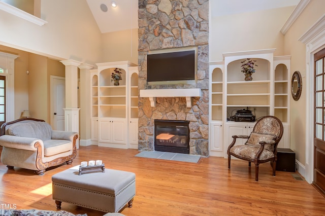living room with a fireplace, wood finished floors, built in features, and high vaulted ceiling
