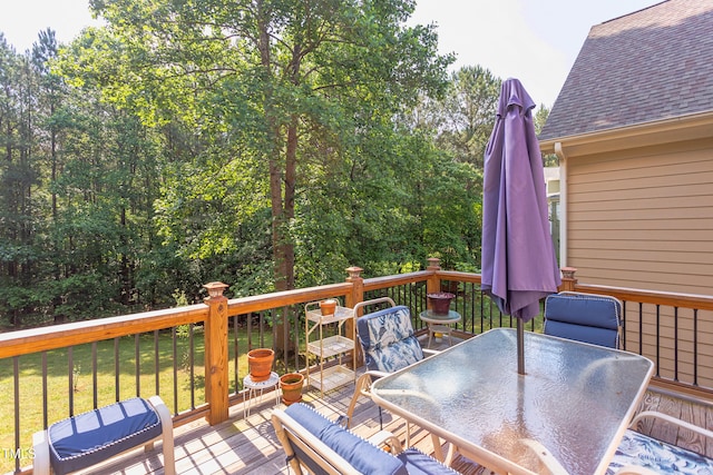 wooden deck featuring outdoor dining space and a lawn
