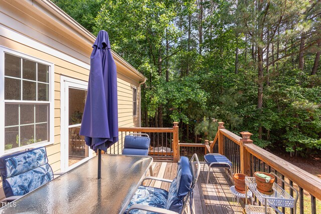 wooden terrace with outdoor dining space and view of scattered trees