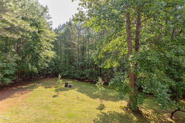 view of grassy yard featuring a forest view