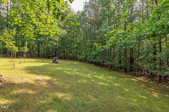 view of green lawn with a wooded view