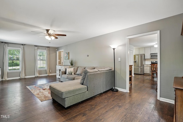 living area with ceiling fan, dark wood-style floors, and baseboards