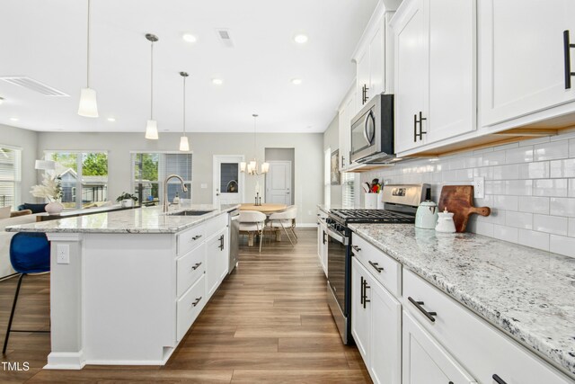 5009 Megara Run, Raleigh, NC 27603 - kitchen featuring stainless steel appliances, a sink, decorative backsplash, white cabinets, and a center island with sink