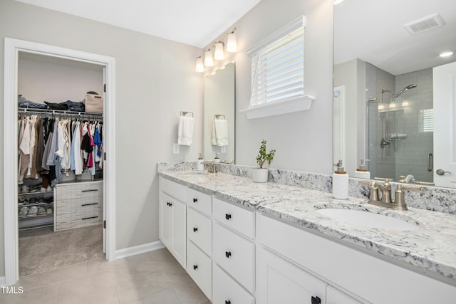 5009 Megara Run, Raleigh, NC 27603 - full bathroom featuring double vanity, a stall shower, a spacious closet, tile patterned floors, and baseboards