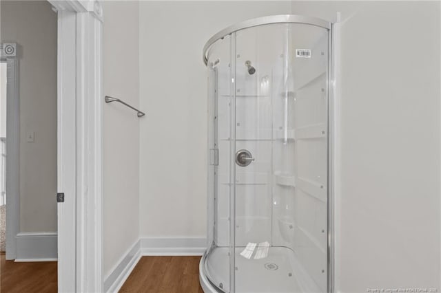 full bathroom featuring baseboards, a stall shower, and wood finished floors