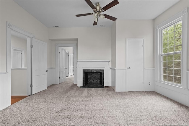 unfurnished living room featuring a fireplace with flush hearth, a ceiling fan, carpet flooring, and visible vents
