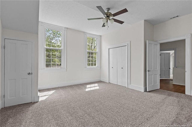 unfurnished bedroom featuring baseboards, carpet, a closet, and visible vents