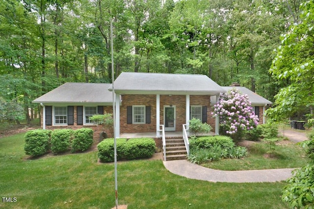 view of front of home featuring covered porch, brick siding, and a front yard